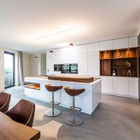 Küche Kücheninsel Großzügig Clean Wand Weiß Matt Walnuß Walnußholz Theke Holz Blanco Spüle BORA Kochfeld Miele Kaffeemaschine Dampfgarer Backofen Arbeitsplatte Glasarbeitsplatte Ausladend Regal Kieppe Planung individuell persönlich Beratung LED LED-Beleuchtung